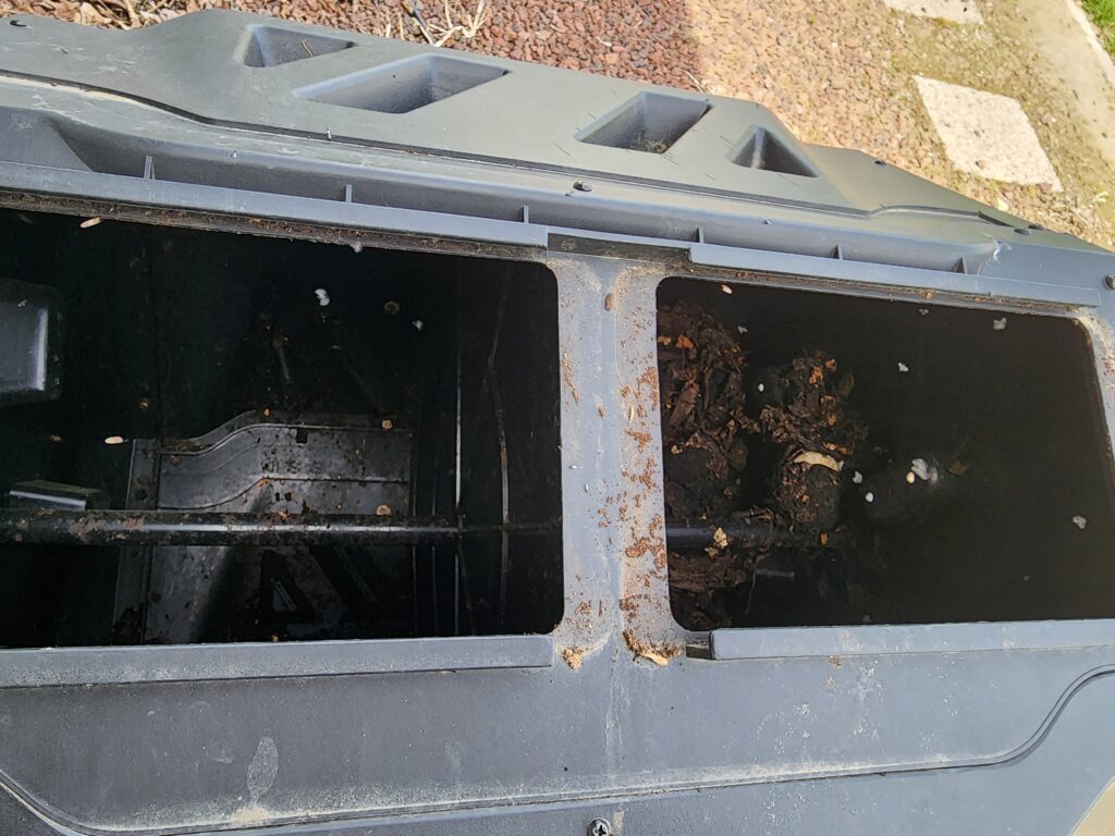 revive compost bin before turning showing compacted clumpy material in a neglected compost tumbler